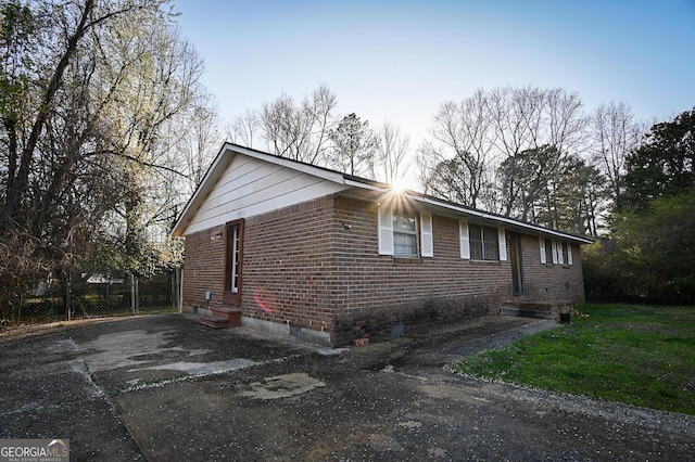 view of front of home with fence, brick siding, and driveway