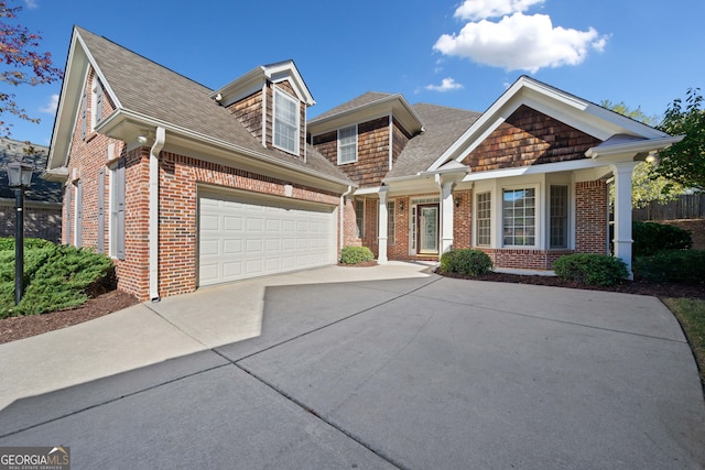 view of front of home with brick siding, driveway, a garage, and roof with shingles