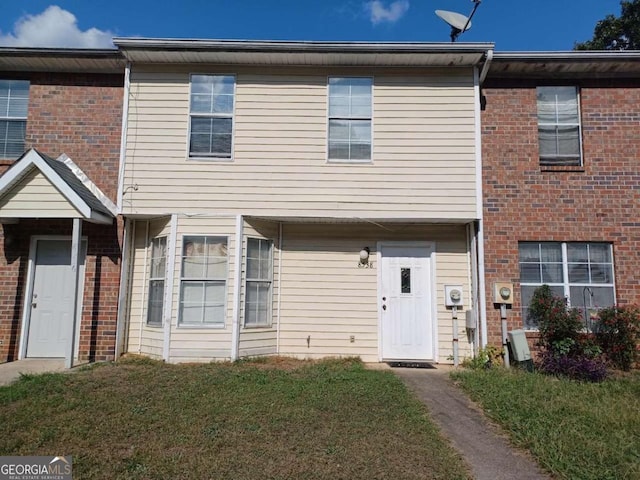 townhome / multi-family property featuring brick siding and a front yard