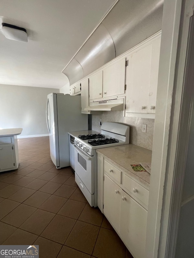 kitchen featuring white appliances, light countertops, white cabinets, under cabinet range hood, and tasteful backsplash