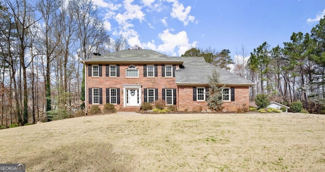 view of front of house with brick siding, a chimney, and a front yard