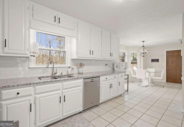 kitchen with stainless steel dishwasher, white cabinets, light tile patterned flooring, and a sink