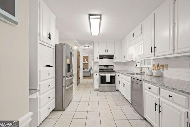 kitchen featuring under cabinet range hood, white cabinetry, stainless steel appliances, and a sink