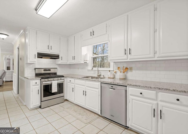 kitchen with a sink, under cabinet range hood, white cabinetry, stainless steel appliances, and light tile patterned floors