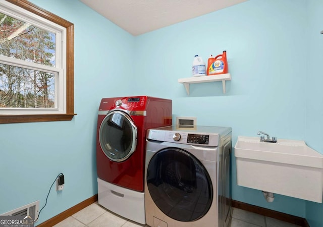 clothes washing area with baseboards, visible vents, washing machine and clothes dryer, laundry area, and a sink