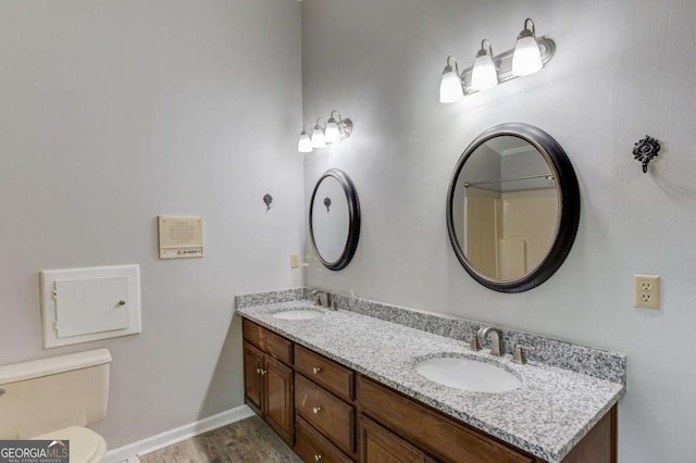 full bath with double vanity, toilet, baseboards, and a sink