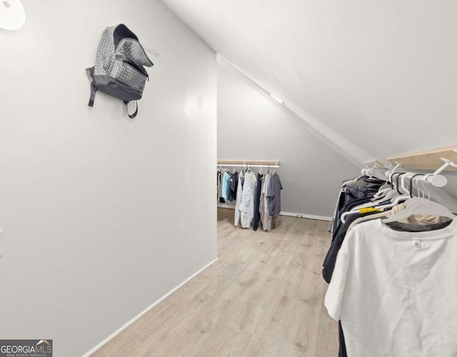 walk in closet featuring wood finished floors and vaulted ceiling