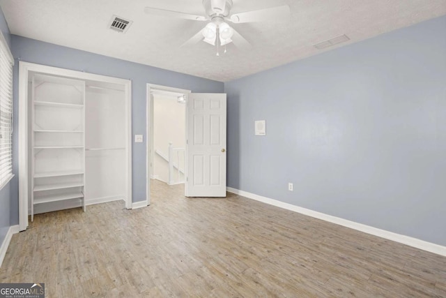 unfurnished bedroom with a closet, baseboards, visible vents, and wood finished floors