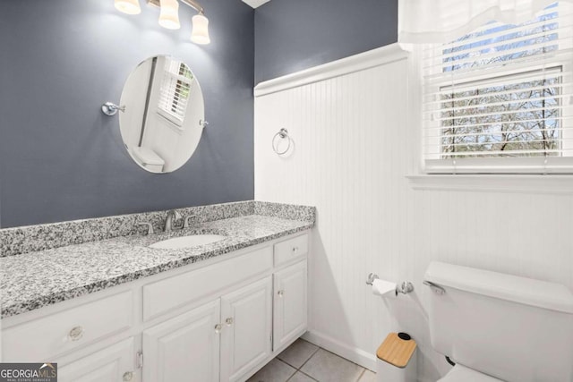 bathroom with a wainscoted wall, toilet, vanity, and tile patterned flooring