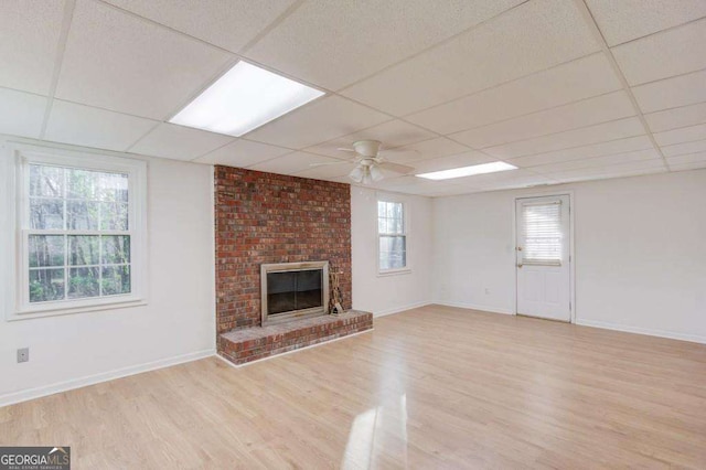 unfurnished living room with light wood-style flooring, a ceiling fan, baseboards, and a drop ceiling