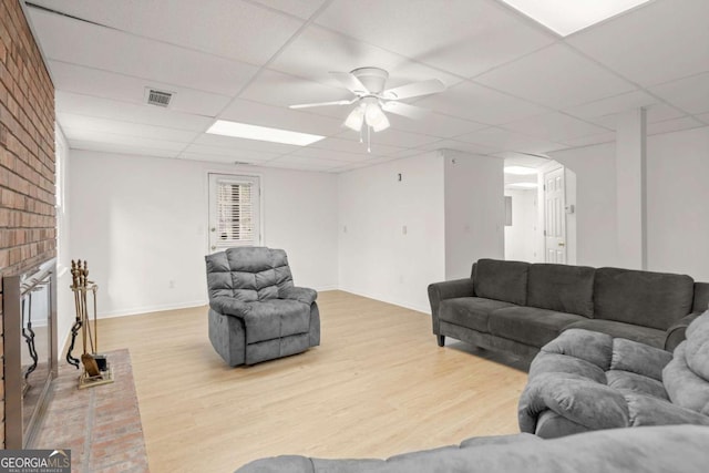 living room featuring a drop ceiling, visible vents, light wood-style flooring, and a ceiling fan