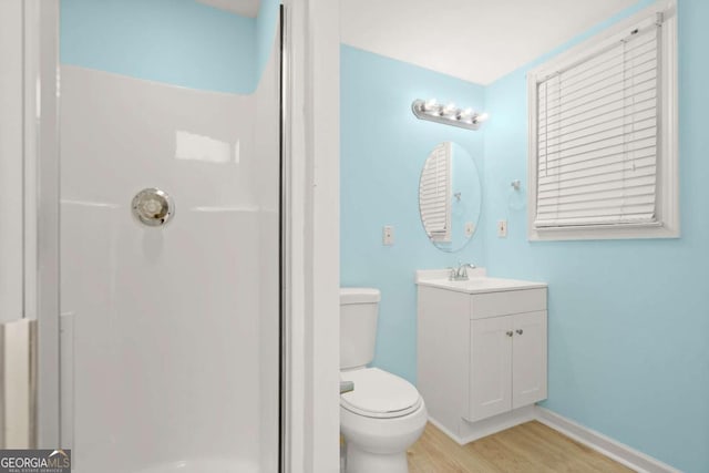 full bathroom with a shower stall, baseboards, toilet, wood finished floors, and vanity