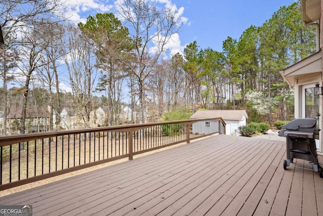 wooden deck featuring an outdoor structure and a grill