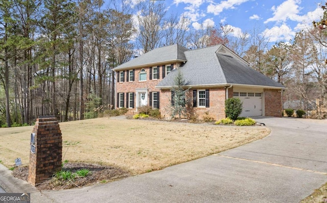 colonial home featuring a front yard, a shingled roof, concrete driveway, a garage, and brick siding