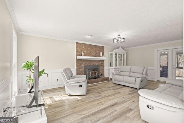 living room with a decorative wall, light wood-type flooring, a wainscoted wall, and ornamental molding