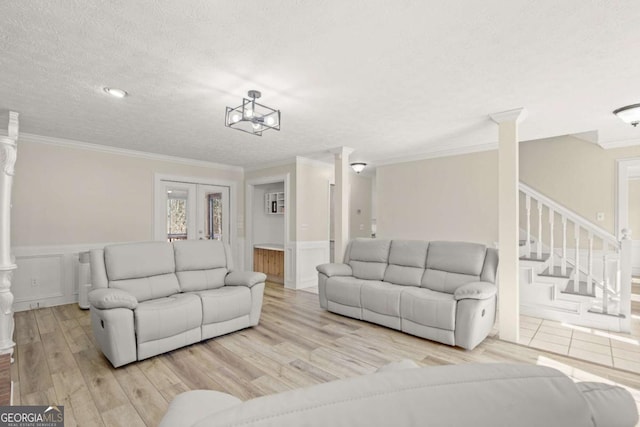 living area with ornamental molding, wood finished floors, a wainscoted wall, and a textured ceiling