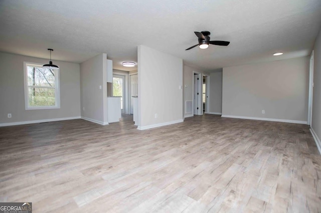 unfurnished living room featuring visible vents, a textured ceiling, wood finished floors, baseboards, and ceiling fan