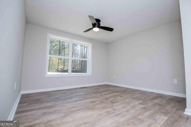 unfurnished room with ceiling fan, visible vents, baseboards, and wood finished floors