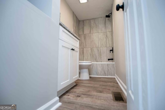 bathroom with visible vents, wood finished floors, tiled shower / bath combo, tile walls, and baseboards