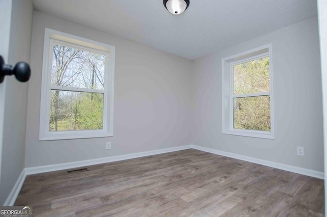 empty room with visible vents, baseboards, and wood finished floors