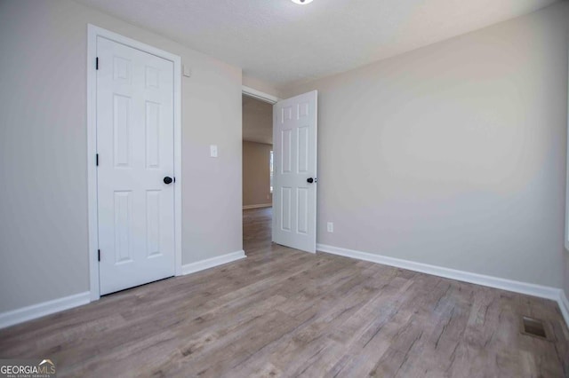 unfurnished bedroom featuring visible vents, wood finished floors, and baseboards