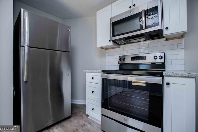 kitchen featuring tasteful backsplash, appliances with stainless steel finishes, and white cabinetry