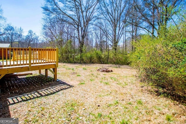 view of yard with a deck and an outdoor fire pit