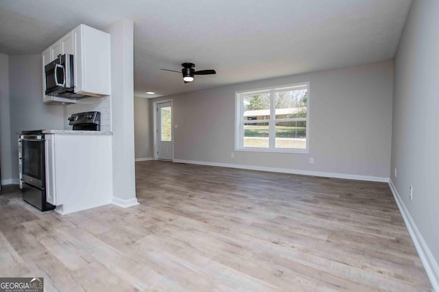 kitchen featuring a ceiling fan, light wood-style floors, appliances with stainless steel finishes, white cabinets, and baseboards