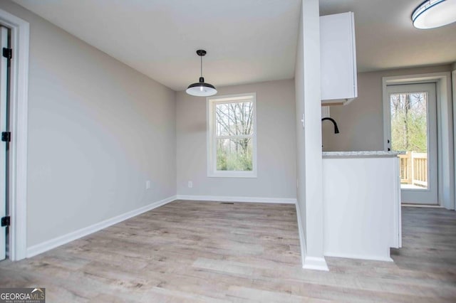 unfurnished dining area with light wood-style flooring and baseboards