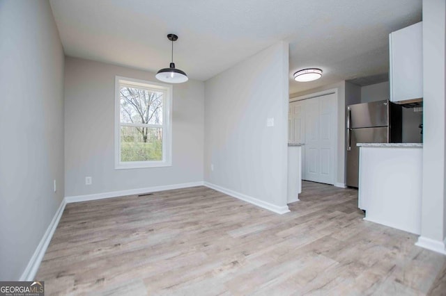 unfurnished dining area with light wood-style flooring and baseboards