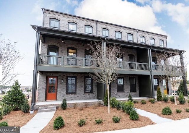 multi unit property featuring brick siding, covered porch, and a balcony