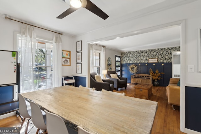 dining area with visible vents, wood finished floors, wallpapered walls, ceiling fan, and an accent wall