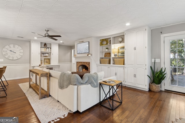 living room featuring built in features, a fireplace, recessed lighting, ceiling fan, and dark wood-type flooring