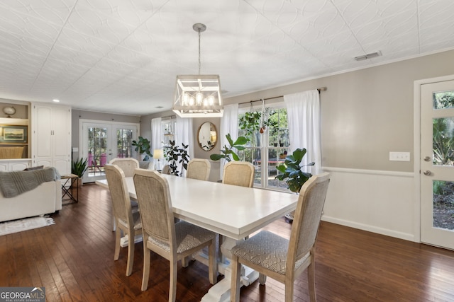 dining room with dark wood-type flooring, visible vents, wainscoting, and a chandelier