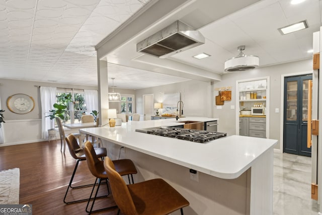 kitchen with a kitchen breakfast bar, gas cooktop, light wood-style floors, light countertops, and white microwave