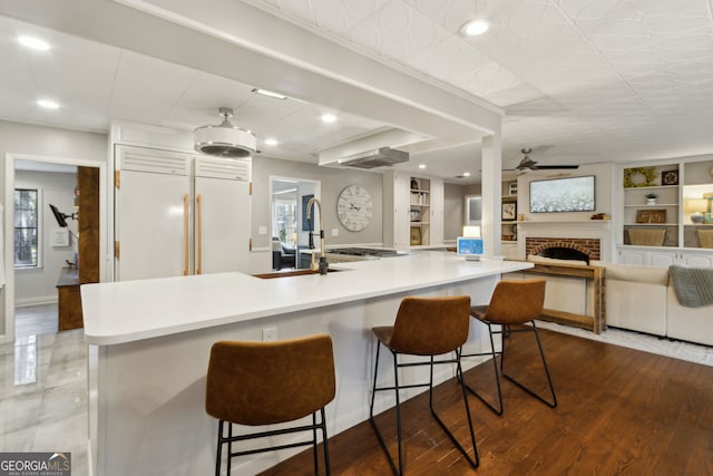 kitchen with built in features, wood finished floors, built in fridge, a fireplace, and ceiling fan