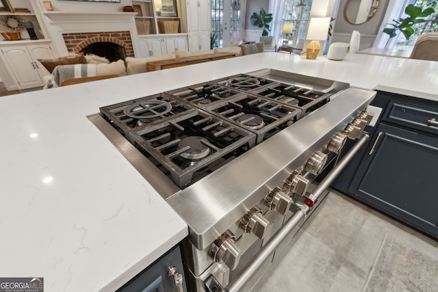 details featuring stovetop, a brick fireplace, and light stone countertops