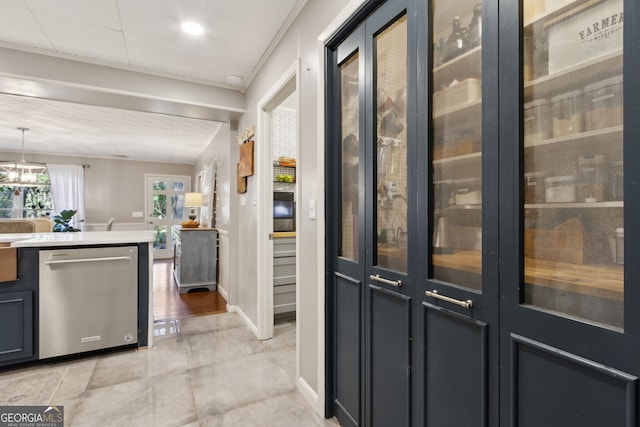 kitchen featuring stainless steel dishwasher, light countertops, glass insert cabinets, baseboards, and hanging light fixtures