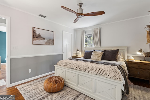 bedroom with visible vents, wood finished floors, crown molding, baseboards, and ceiling fan