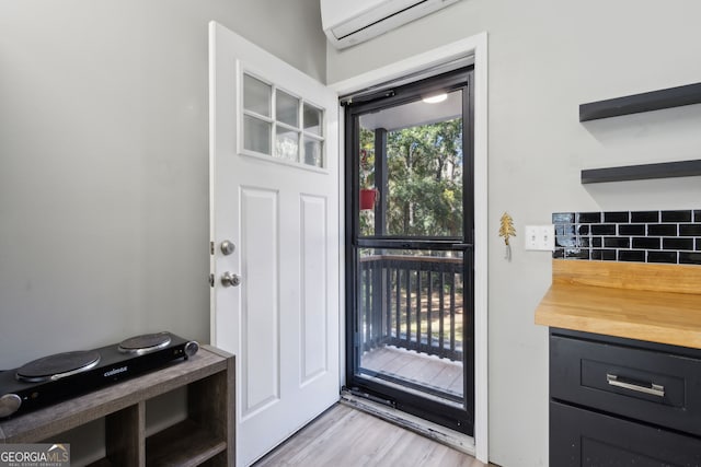 entryway with light wood-style floors and a wall unit AC