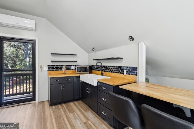 kitchen with open shelves, wood counters, stainless steel microwave, a sink, and a wall unit AC