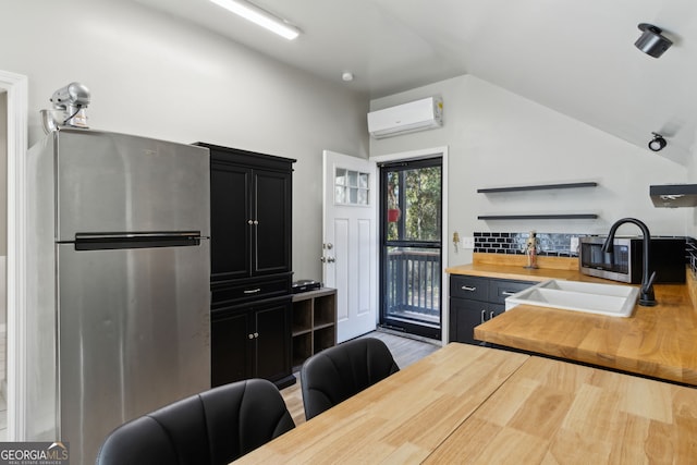 kitchen with a wall mounted air conditioner, lofted ceiling, appliances with stainless steel finishes, wood counters, and dark cabinets