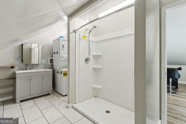 full bath featuring vanity, a shower stall, backsplash, and stacked washing maching and dryer