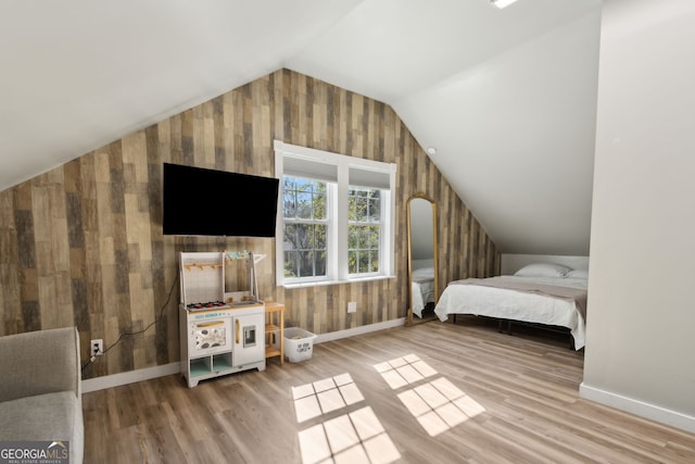 bedroom with vaulted ceiling, wood finished floors, and baseboards