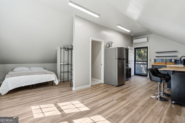 interior space featuring a wall unit AC, light wood finished floors, wooden counters, lofted ceiling, and appliances with stainless steel finishes