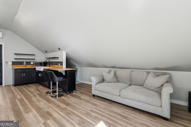 office area with baseboards, light wood-style flooring, and vaulted ceiling