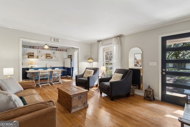 living room with ornamental molding, baseboards, and wood finished floors