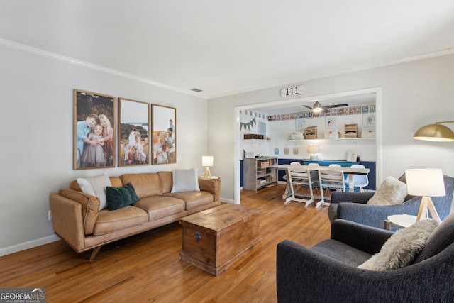 living area with wood finished floors, visible vents, and ornamental molding