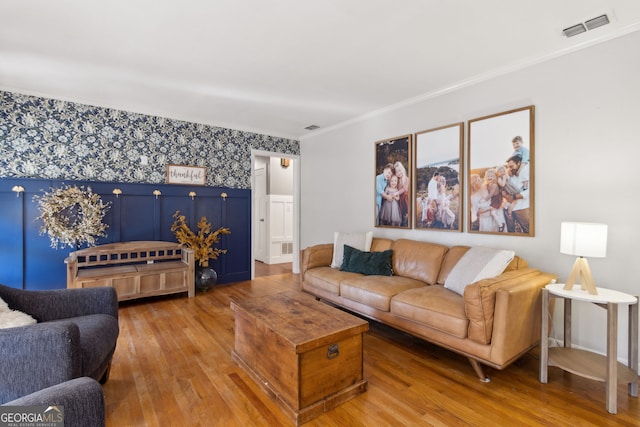 living area featuring wallpapered walls, hardwood / wood-style flooring, crown molding, and visible vents