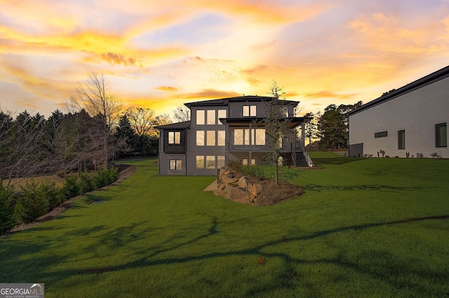 rear view of house featuring a yard and stucco siding